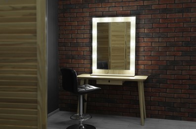 Photo of Mirror with light bulbs, table and chair in makeup room