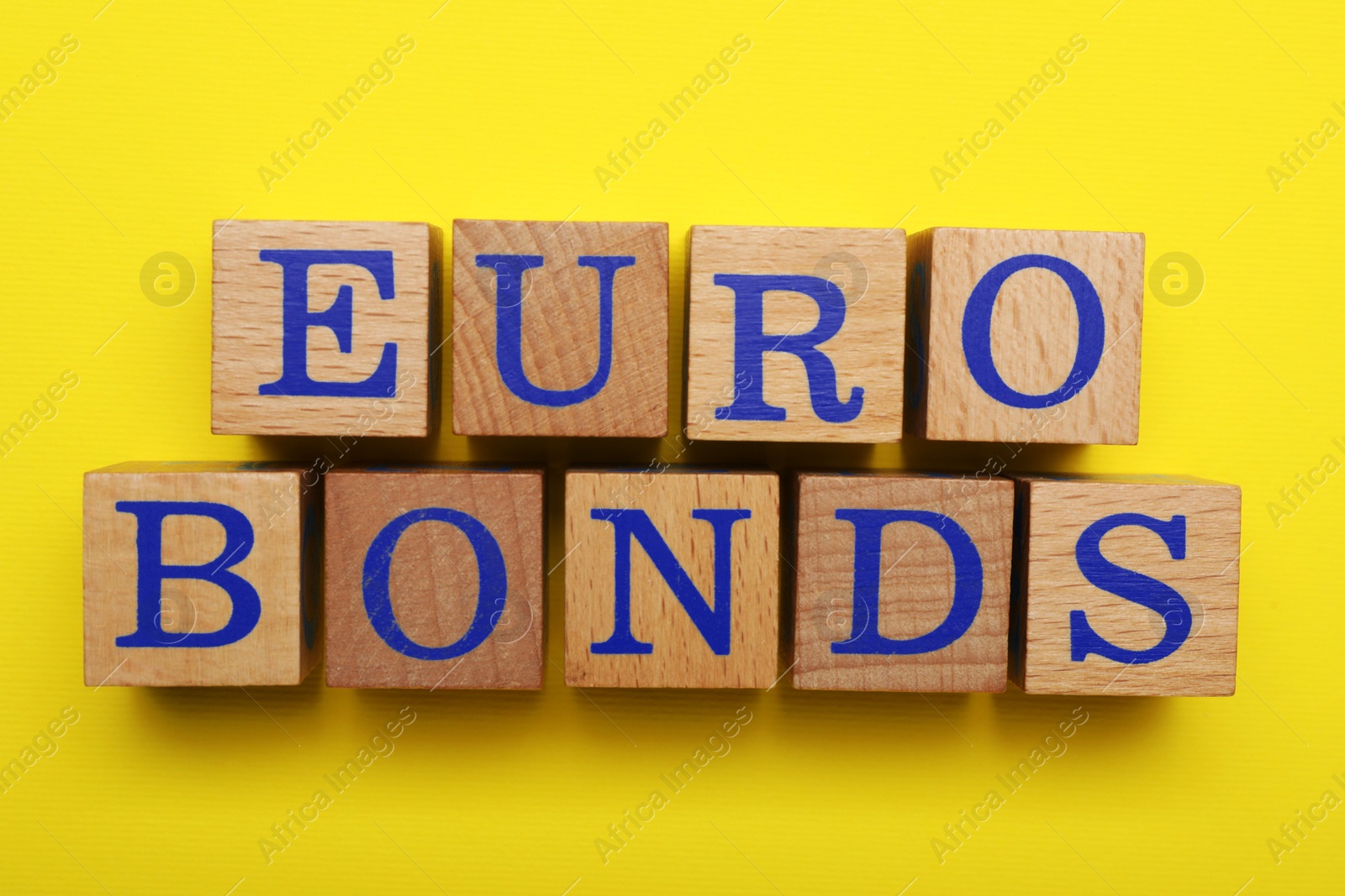 Photo of Word Eurobonds made of wooden cubes with letters on yellow background, flat lay