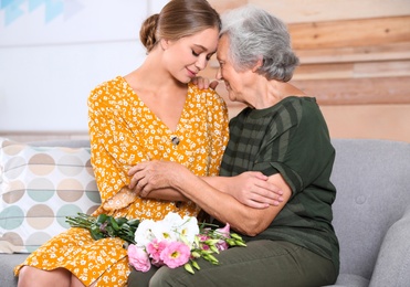 Photo of Young woman congratulating her senior mom at home. Happy Mother's Day