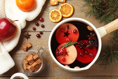 Photo of Saucepan with tasty mulled wine on wooden table, flat lay