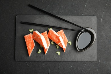 Photo of Fresh crab sticks with celery served on black table, top view