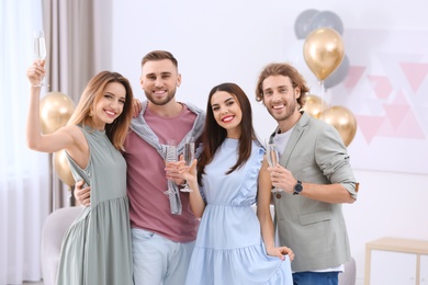 Happy friends with champagne in glasses at home