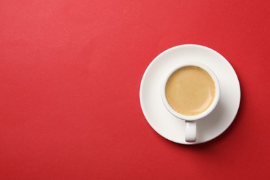 Aromatic coffee in cup on red background, top view. Space for text