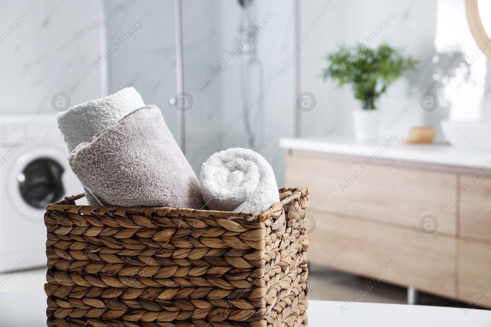Photo of Wicker basket with clean soft towels in bathroom. Space for text