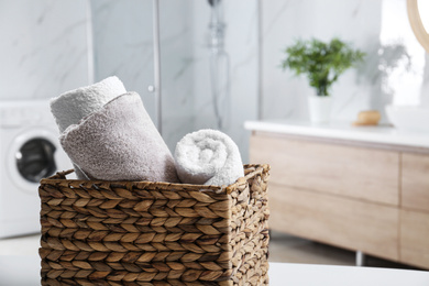 Wicker basket with clean soft towels in bathroom. Space for text