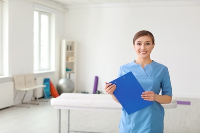 Photo of Young physiotherapist with clipboard in rehabilitation center