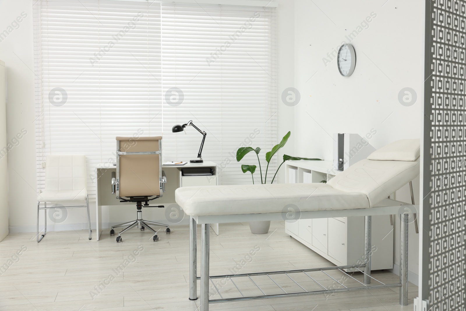 Photo of Modern medical office with doctor's workplace and examination table in clinic