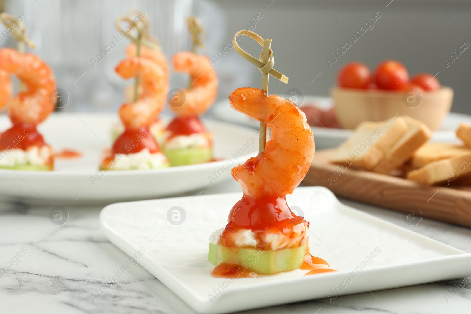 Photo of Tasty canape with shrimp, vegetables and cream cheese on white marble table