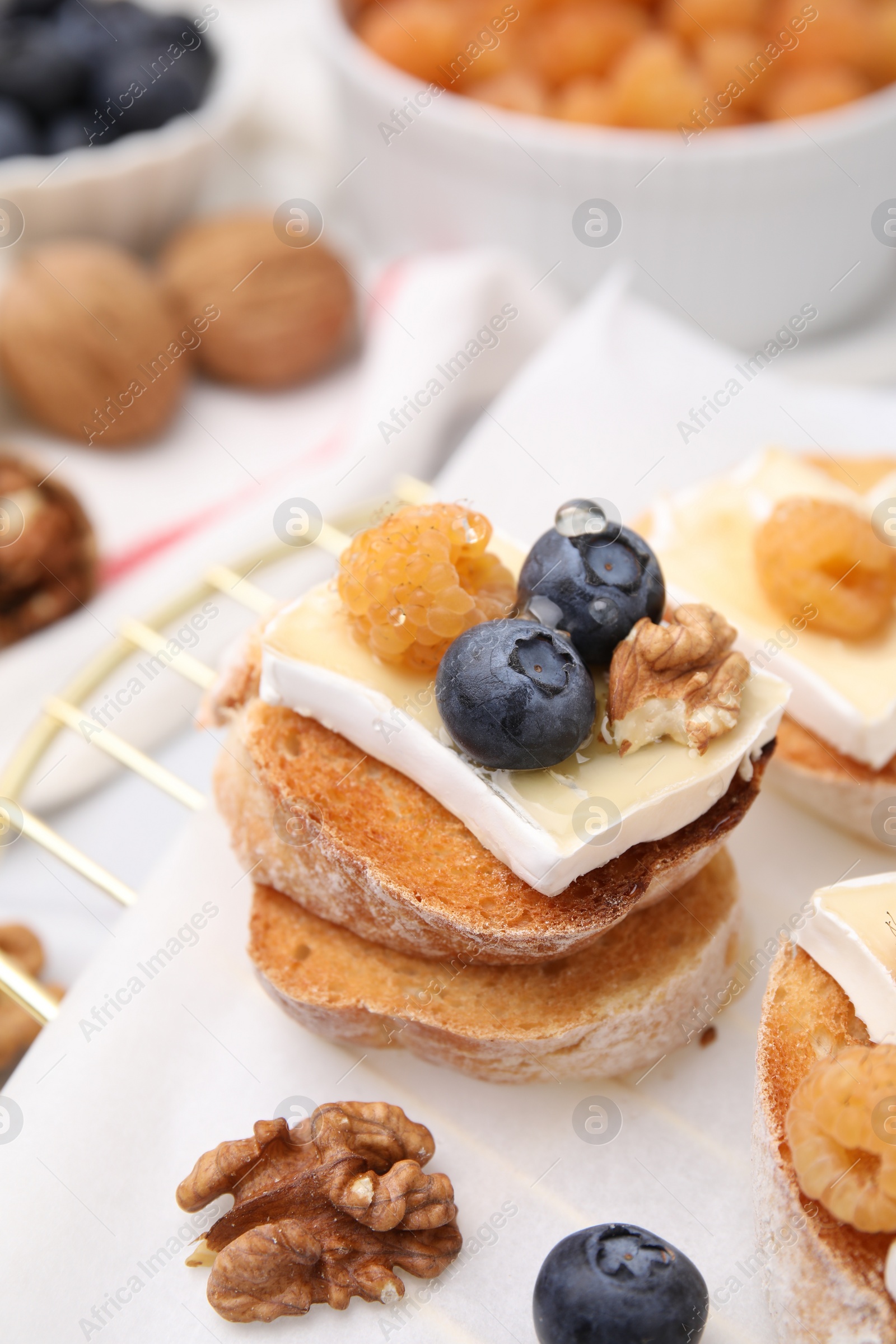 Photo of Tasty sandwich with brie cheese, fresh berries and walnuts on table, closeup