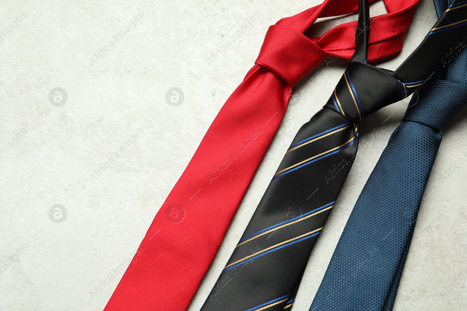 Photo of Different neckties on light textured table, flat lay. Space for text