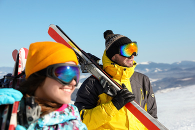 Photo of Happy couple with ski equipment in mountains. Winter vacation
