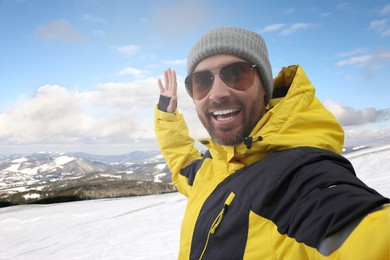 Image of Smiling man in sunglasses taking selfie in mountains