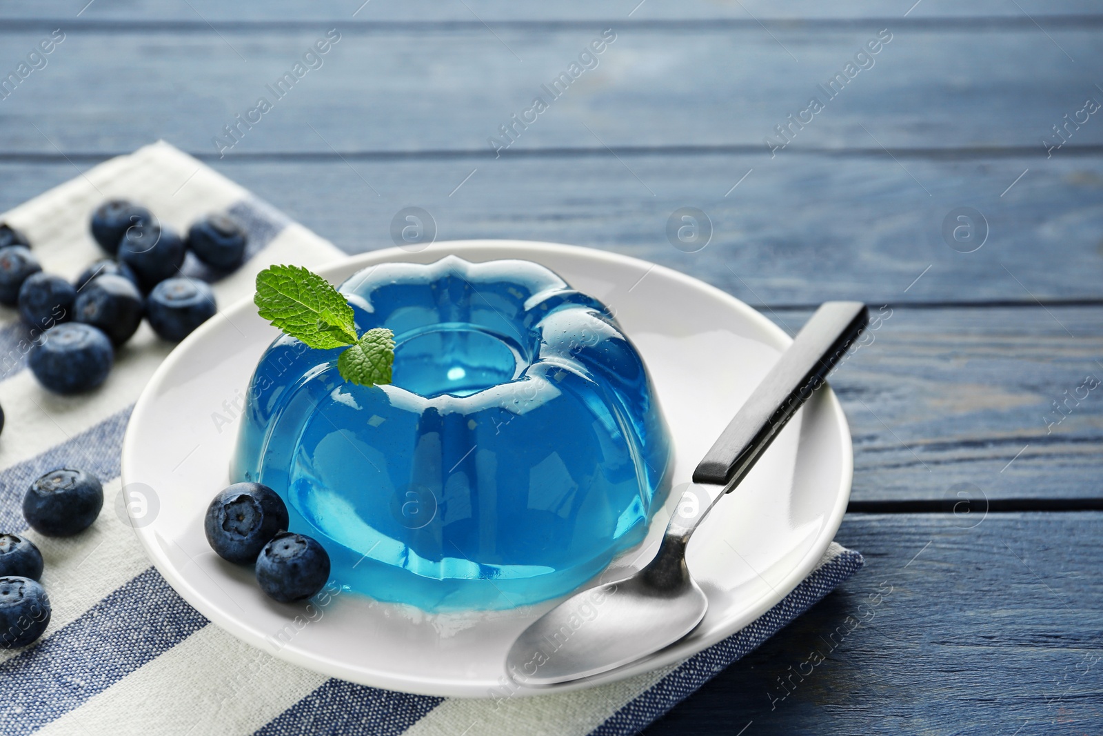 Photo of Plate of delicious blue jelly with berries on color wooden background