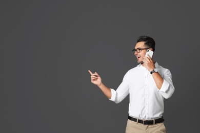 Photo of Handsome young man talking on phone against black background. Space for text