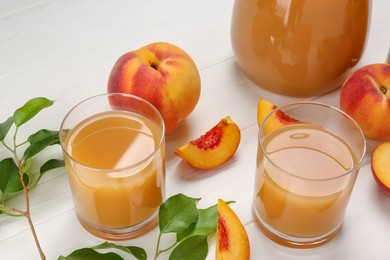 Delicious peach juice, fresh fruits and leaves on white wooden table