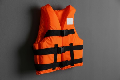 Photo of Orange life jacket on grey background. Personal flotation device