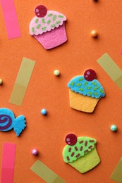 Photo of Flat lay composition with felt cupcakes on orange background