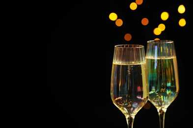 Photo of Glasses of champagne on black background, closeup. Space for text
