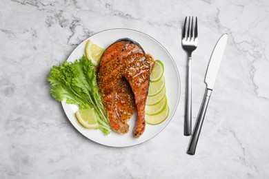 Photo of Tasty salmon steak with sauce, citrus slices and lettuce served on white marble table, flat lay