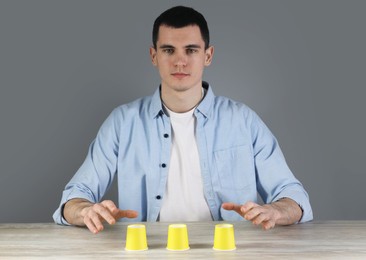 Photo of Man playing shell game at wooden table