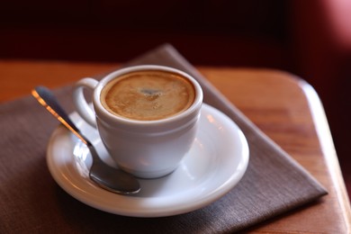 Cup of hot aromatic coffee served on wooden table in cafe. Space for text