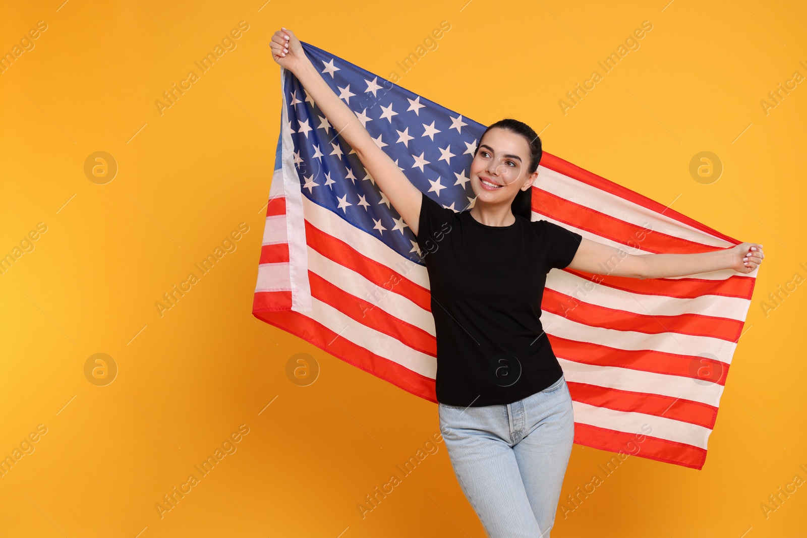 Photo of 4th of July - Independence Day of USA. Happy woman with American flag on yellow background, space for text