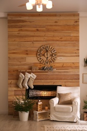 Potted fir trees and Christmas decorations in room with fireplace. Stylish interior design