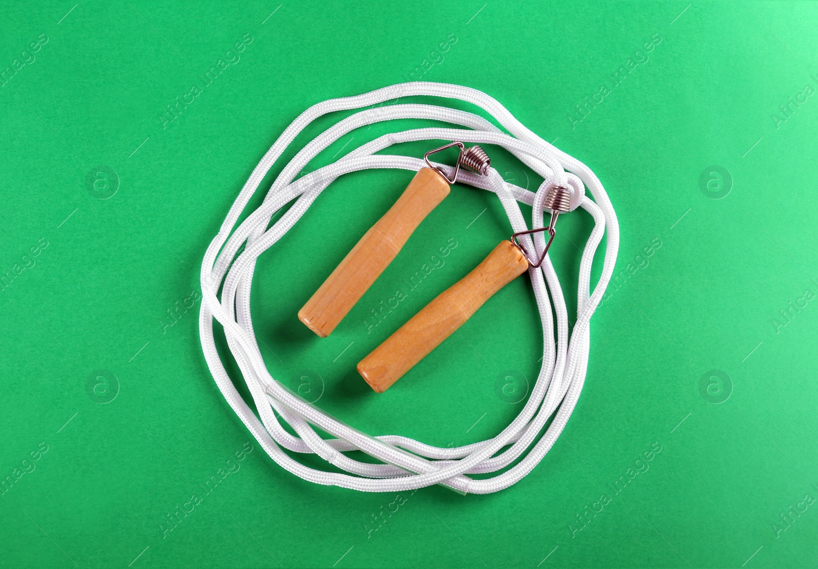 Photo of Skipping rope on green background, top view. Sports equipment