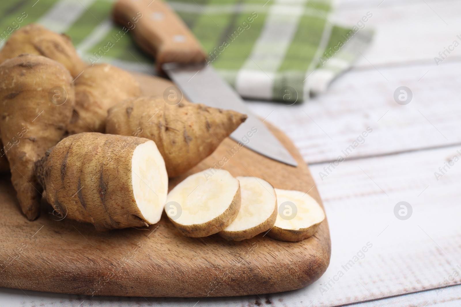 Photo of Whole and cut turnip rooted chervil tubers on light wooden table, closeup. Space for text