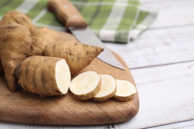 Photo of Whole and cut turnip rooted chervil tubers on light wooden table, closeup. Space for text