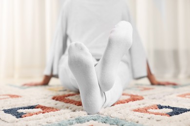 Photo of Woman in stylish white socks on carpet indoors, closeup