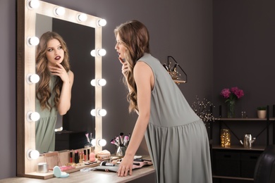 Young beautiful woman near mirror in makeup room