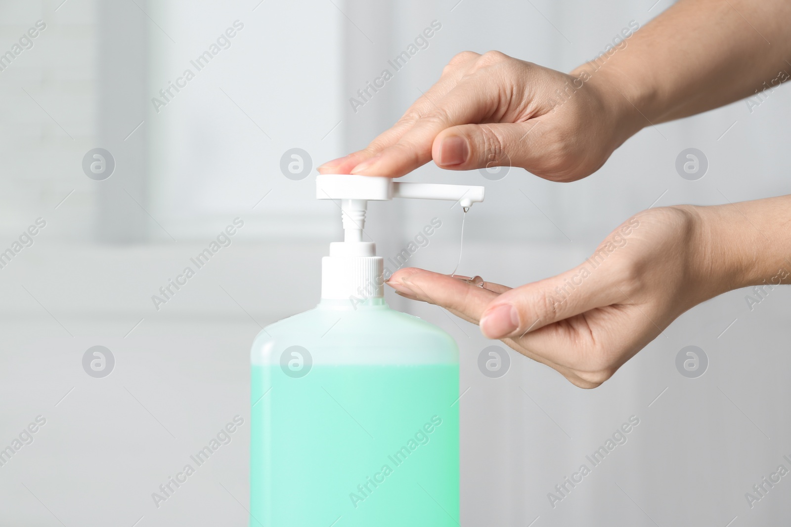 Photo of Woman applying antiseptic gel on hand indoors, closeup