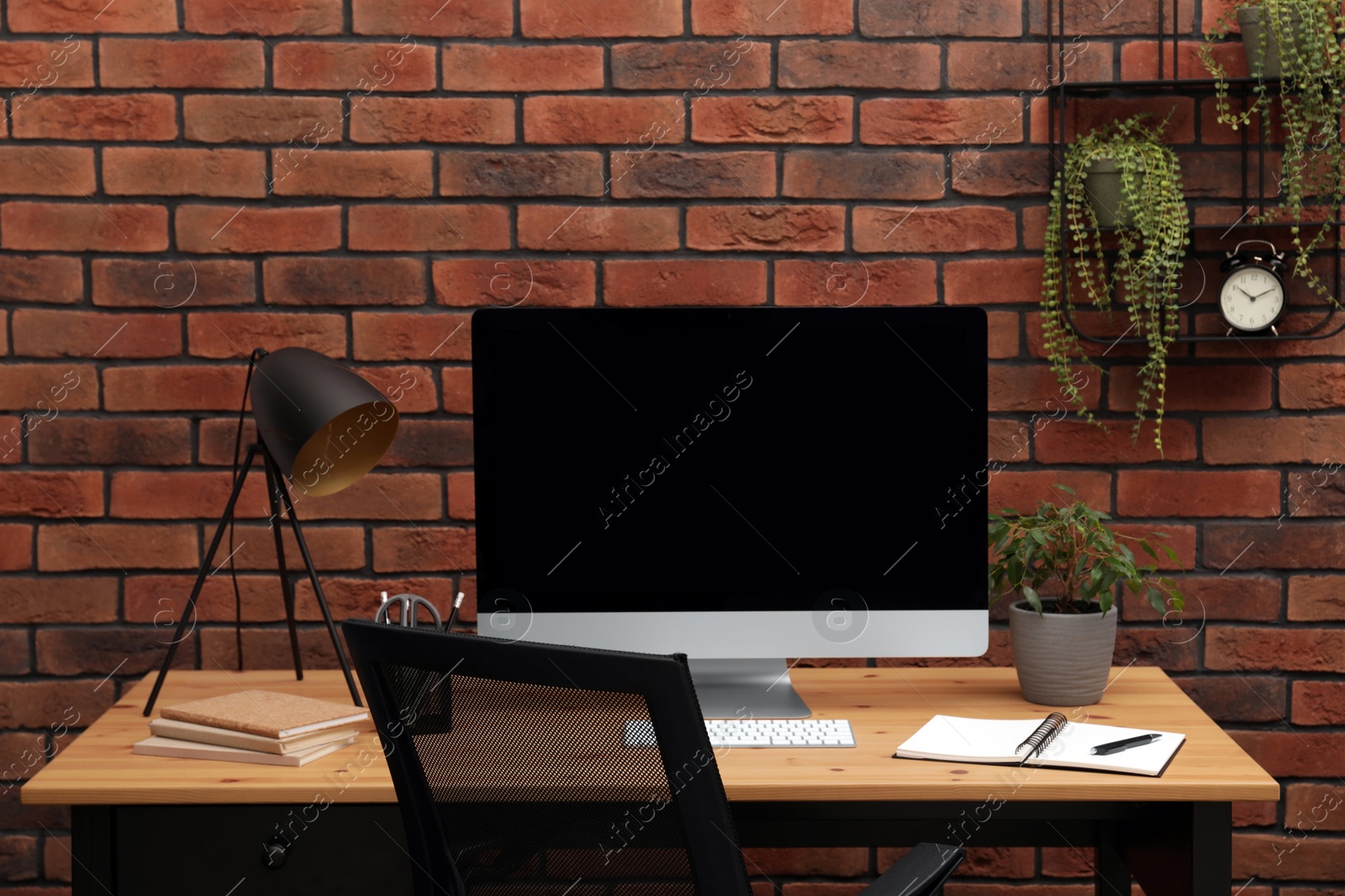 Photo of Cozy workplace with computer and lamp on desk at home