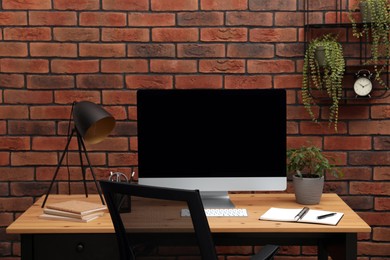 Photo of Cozy workplace with computer and lamp on desk at home