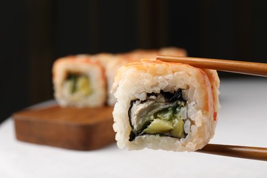 Photo of Holding delicious sushi roll with chopsticks, closeup. Space for text