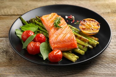 Photo of Tasty grilled salmon with tomatoes, asparagus and spices on wooden table