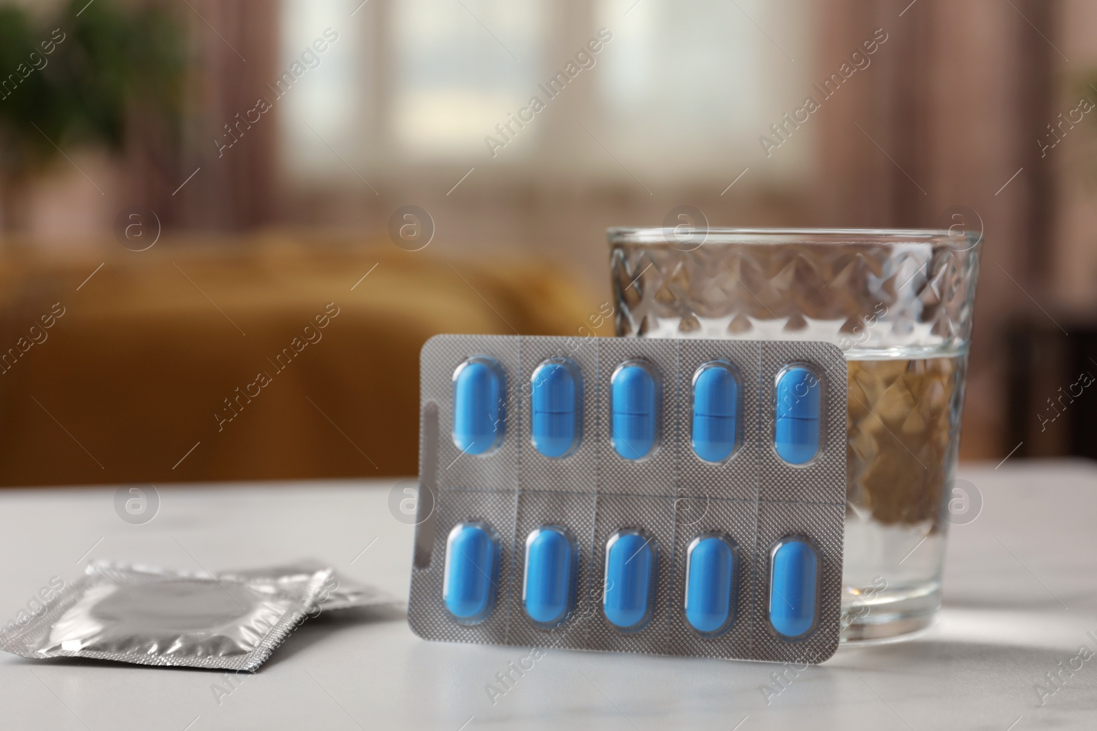 Photo of Glass of water, condoms and pills on white table indoors, closeup with space for text. Potency problem concept