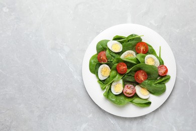 Photo of Delicious salad with boiled eggs, tomatoes and spinach on light grey table, top view. Space for text