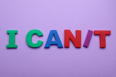 Photo of Motivation concept. Changing phrase from I Can't into I Can by adding slash symbol on violet background, flat lay
