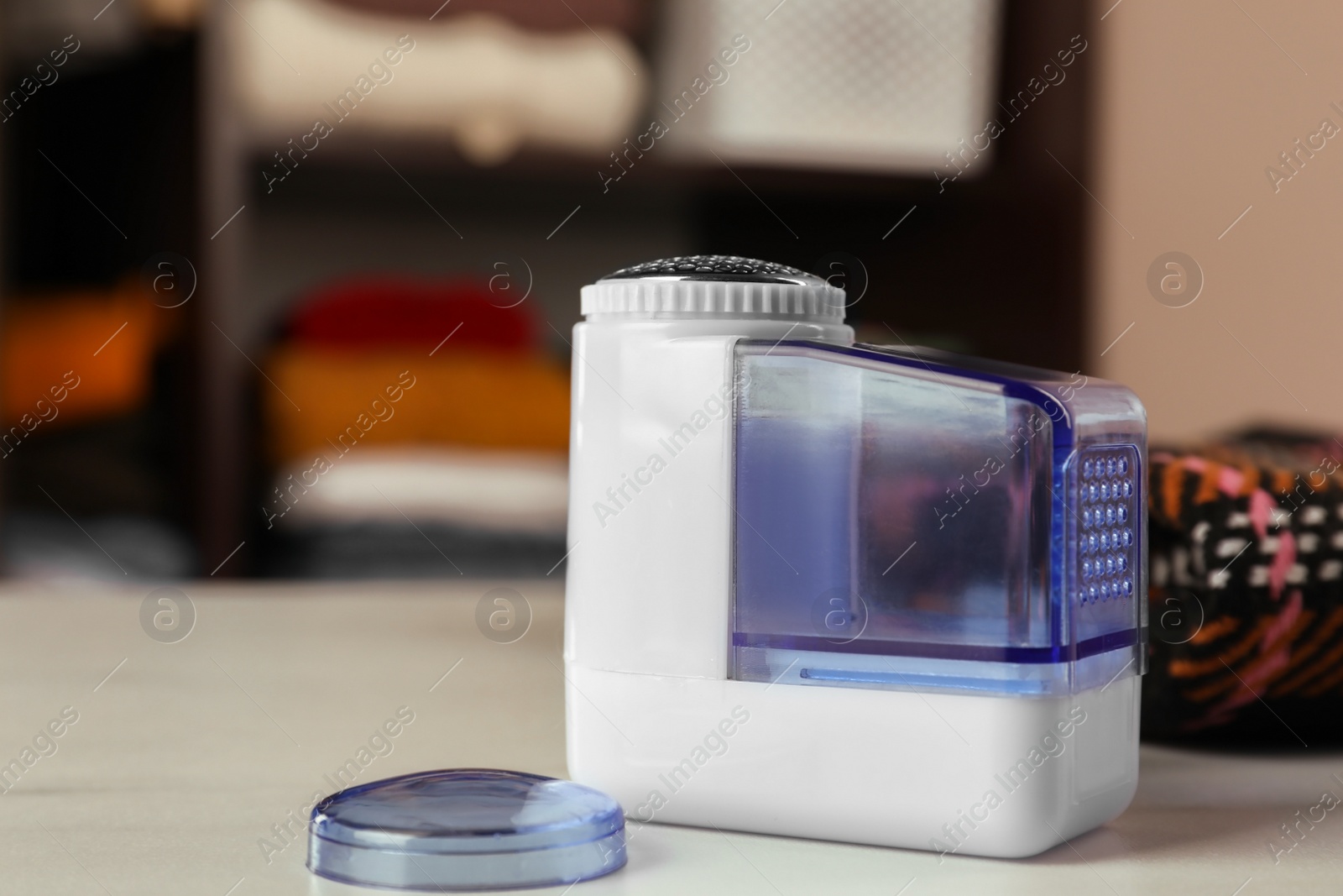 Photo of Modern fabric shaver and cloth on white table indoors, closeup. Space for text