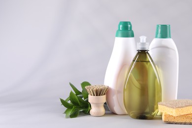 Photo of Bottles of cleaning product, brush and sponges on white background. Space for text