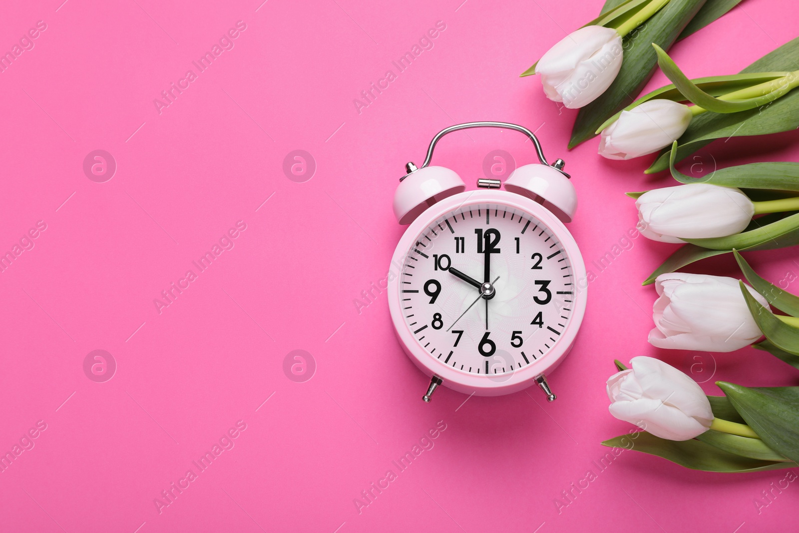 Photo of Alarm clock and beautiful tulips on pink background, flat lay with space for text. Spring time