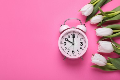 Photo of Alarm clock and beautiful tulips on pink background, flat lay with space for text. Spring time