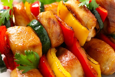 Photo of Delicious chicken shish kebabs with vegetables on plate, closeup