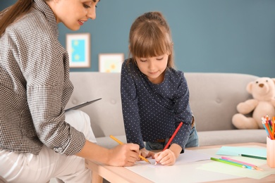Photo of Female psychologist working with cute little girl in office