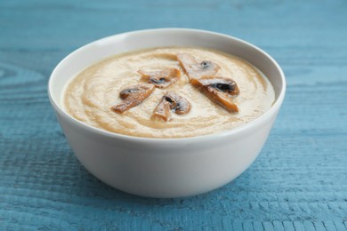 Photo of Delicious mushroom cream soup on light grey wooden table, closeup