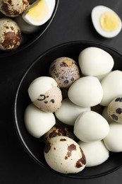 Photo of Unpeeled and peeled hard boiled quail eggs on black table, flat lay