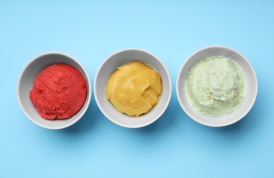 Different delicious ice creams on light blue background, flat lay