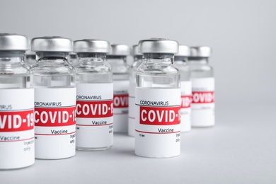 Glass vials with COVID-19 vaccine on light grey background